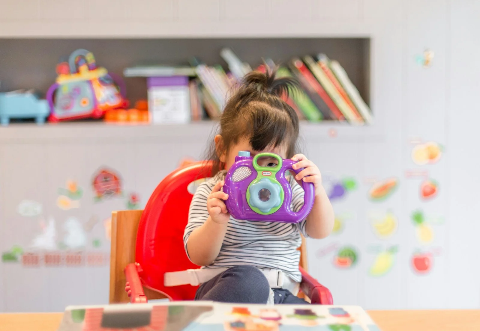 A young child playing with a colourful toy camera